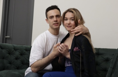 Teen with big bangs and a handsome boyfriend sitting on their loveseat.