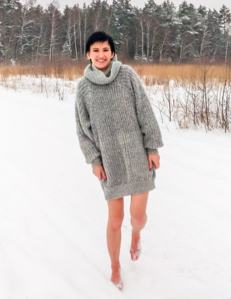 Claudia, a naked girl with short black hair, kneels on snow-covered ground while being gagged.