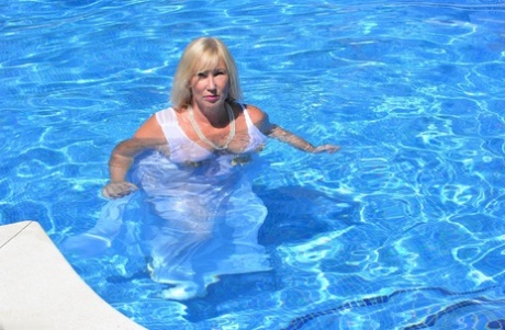 Blonde Melody, who is overweight and looks stunning in a flowing white gown, enjoys swimming at the pool.