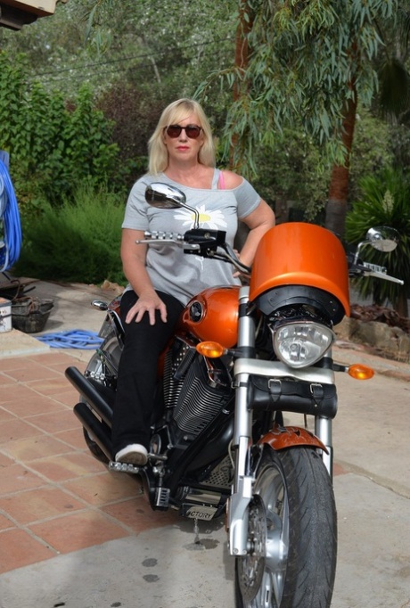 Melody, a blonde who is overweight, goes without a top after getting off her motorcycle.
