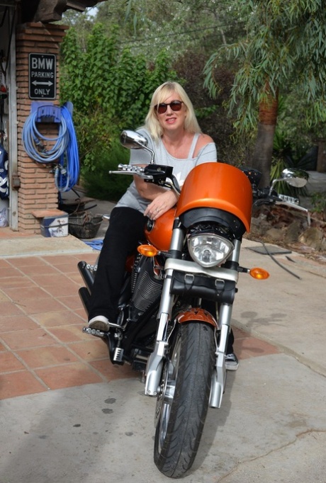 After getting off her motorcycle, Melody, a blonde who is overweight, goes without a top.
