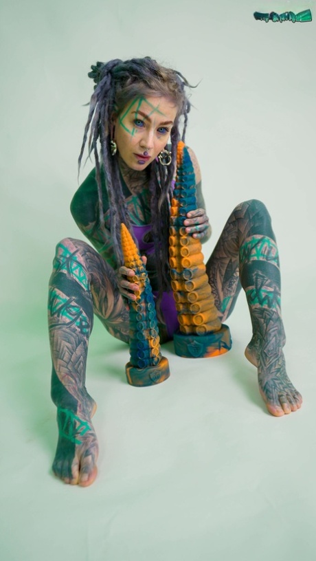 Сильно татуированная девушка Anuskatzz держит пару игрушек taintacle в обнаженном виде