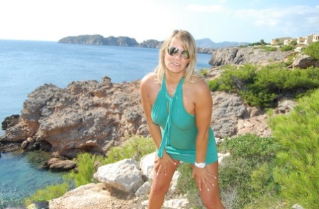 While climbing rocks near the sea, Middle Aged blonde Sweet Susi is seen in the photo getting naked.