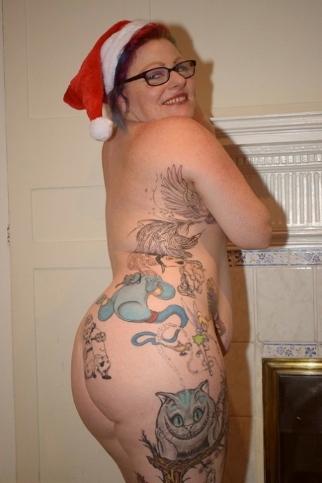 A Santa is donned by an elderly woman with tattoos who tries to get naked in her bikini pose.