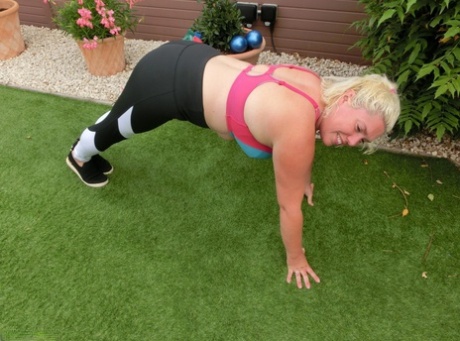 While exercising in her backyard, Barby, a slim blonde woman, goes for a naked look.