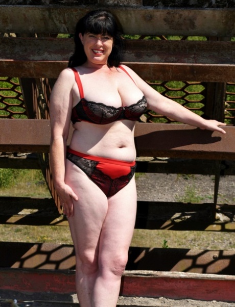 After exposing herself in the open air, Juicey Janey, a mature British woman, holds her large breasts.
