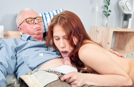 A young redhead teasing an elderly man before having sex with him on the bed.