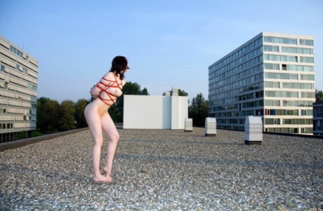 Left alone on a rooftop, this naked woman is tied up with red rope and left naked all alone.