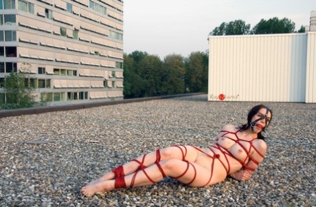 Left alone on a rooftop, this naked woman is tied up with red rope and left naked all alone.