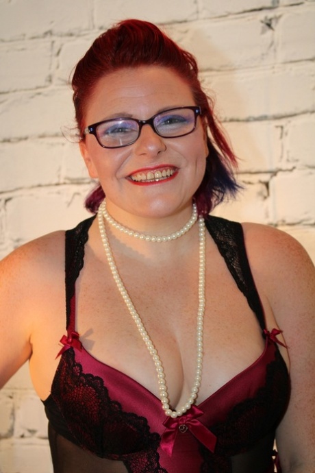 With glasses and nylons, chubby redhead looses her tits from lingerie.