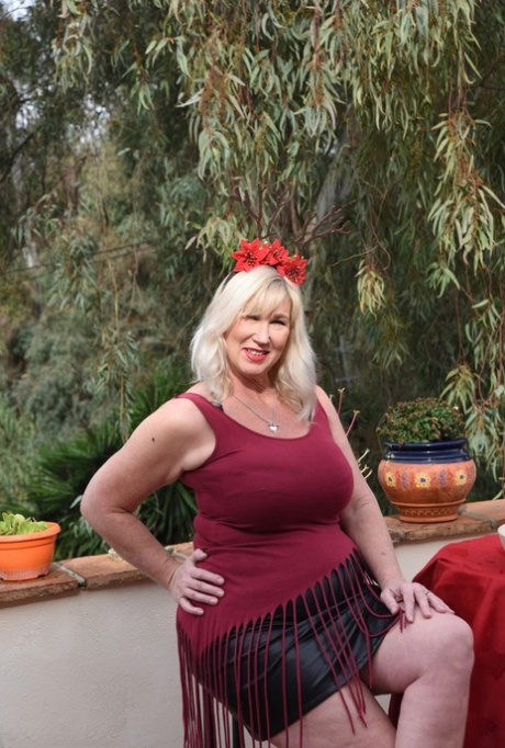 A leather skirt and a bra are worn by an older blonde fatty Melody while lounging on a patio.