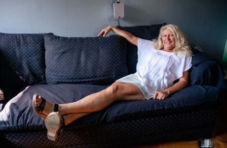 The older blonde, Annie Griffith and her male partner have sex on the couch.