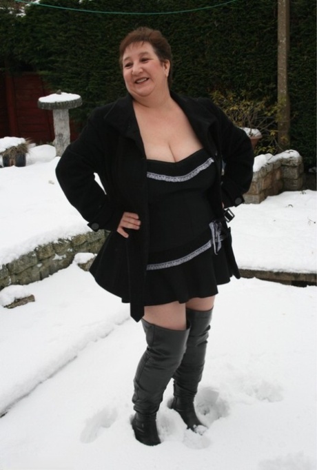 On snow-covered terrain, Kinky Carol from the UK, who is aged fatty, seizes over-the-knee boots.