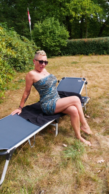 A horny woman masturbates on her loungers in the backyard while being alone.