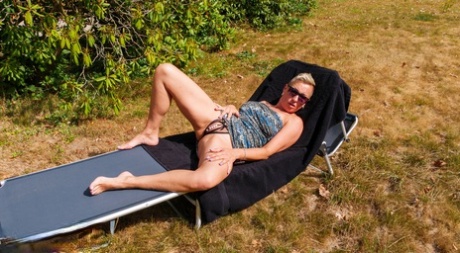 Uncommon woman masturbates on a backyard lounge chair while being alone.