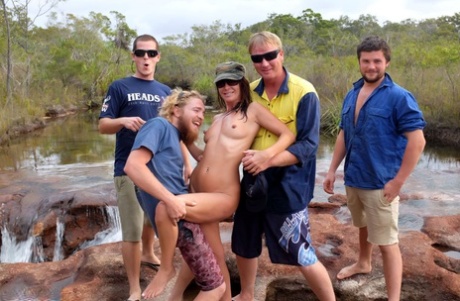 A group of men give Roxeanne a good kiss before she drinks some beer. She's the naked girl.