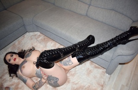 Tattooed brunette Lucy Ravenblood is seen in over the knee latex boots while wearing them without any clothes on.