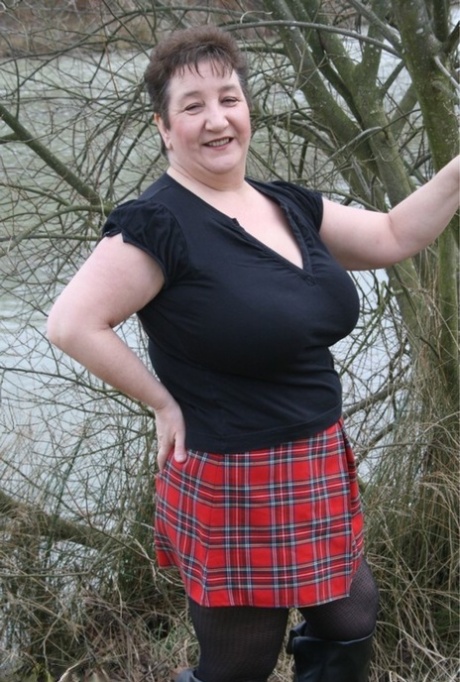 Taking off her shirt in the water, Kinky Carol, an overweight British woman, wears a plaid skirt.