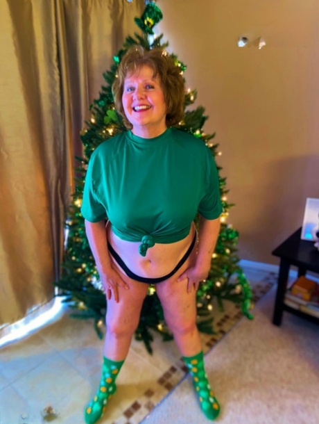 Young Busty Bliss, an Irish plumper of adulthood goes without clothing in front of a Christmas tree.