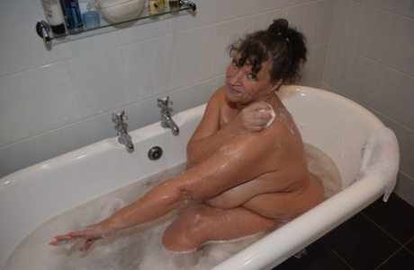 During a bath, the mature and overweight Busty Kim displays her large breasts.