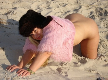 Blonde curvy, who looks chubby blonde, exhibits her pusses and stomach on a sandy bank.