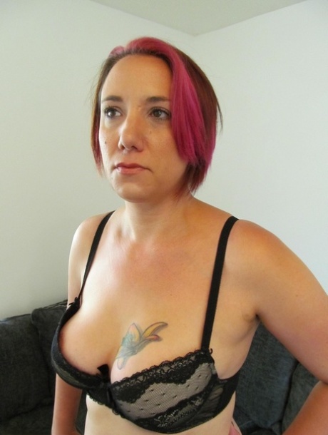 Sara Banks, a young and mature woman with dyed hair, releases her pussy and tits from the lingerie.