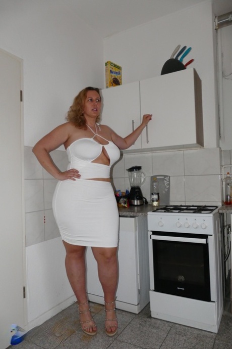 In a kitchen, Kathy D plays with her big tits before engaging in sexual activity.