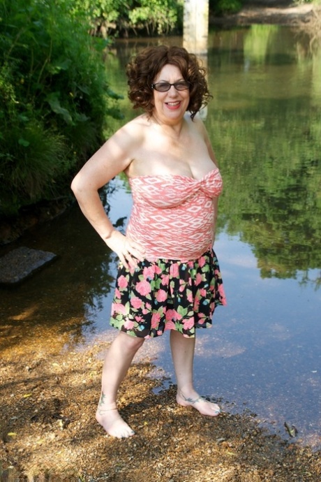 A woman who is older gets her natural tits out by entering shallow water, where she falls in.