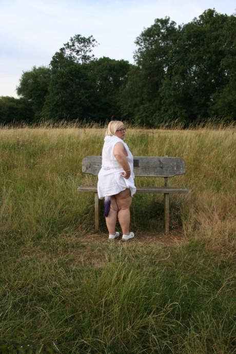 Lexie Cummings, a plump British woman, takes on weight by sitting on a bench in a field.