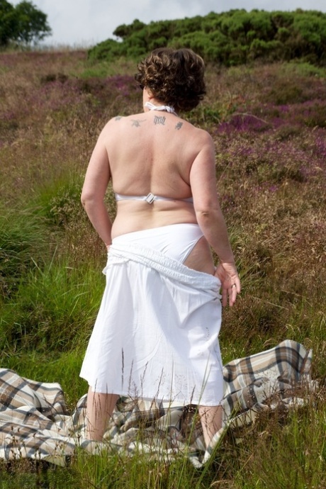 The old lady Dirty Doctor is pictured naked on a blanket in the middle of a field without tops.