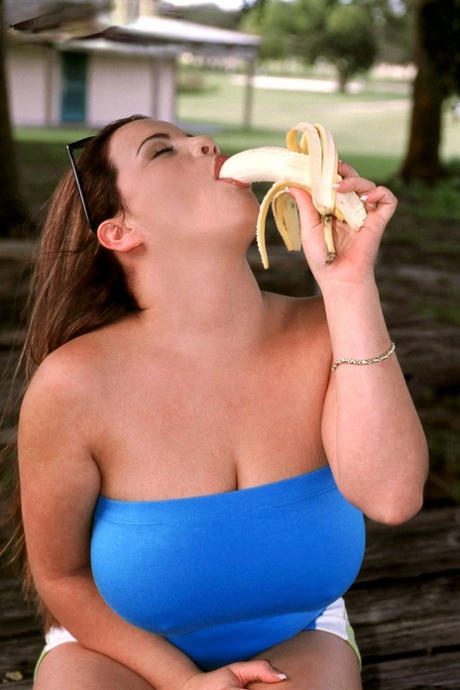 Thick chick Annie Swanson eats a banana before baring her breasts in a park