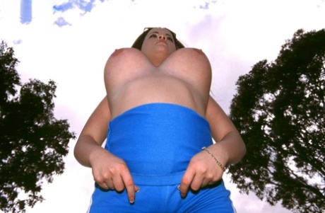 While lounging in a park, Annie Swanson, the petite girl with size 10, consumes some banana and raise her breast.