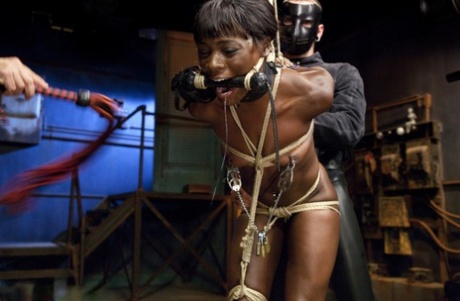 Flogged: Restrained black girl Ana Foxxx gets a fist pump and anviled by two other men.