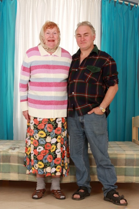 In a picture, a fat elderly woman dressed in a long skirt and socks while holding her cane, complete with her hair and gloves.