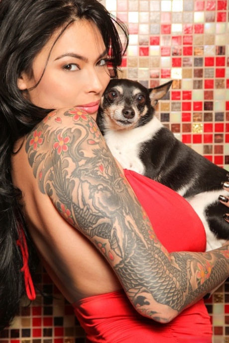 Prior to cuddling with a dog and a man, the tattooed brunette models herself in an alligator suit and short red dress.