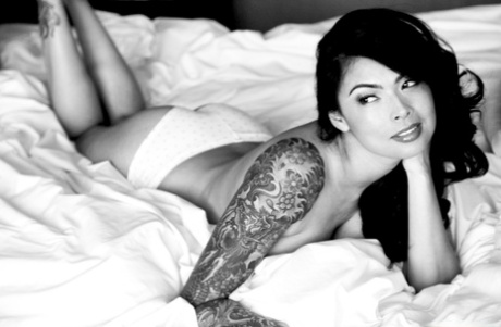 A SFW photo session features Tera Patrick, an Asian tattooed MILF, posing on her bed.