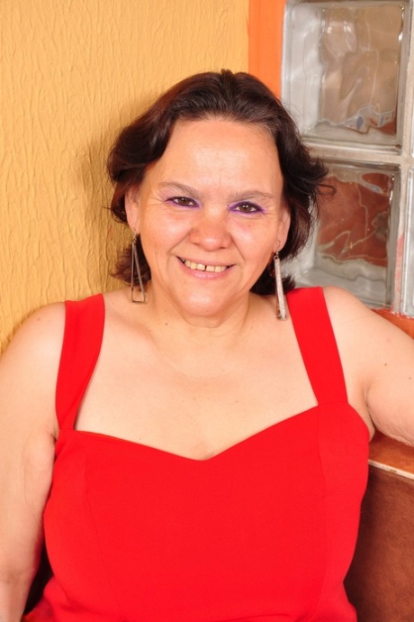 A Latin housewife who is overweight removes her red clothing to pose in lingerie and hose.