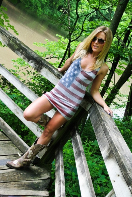 Amateur blonde slut Madden poses in open air wearing a short skirt, thong, and boots.