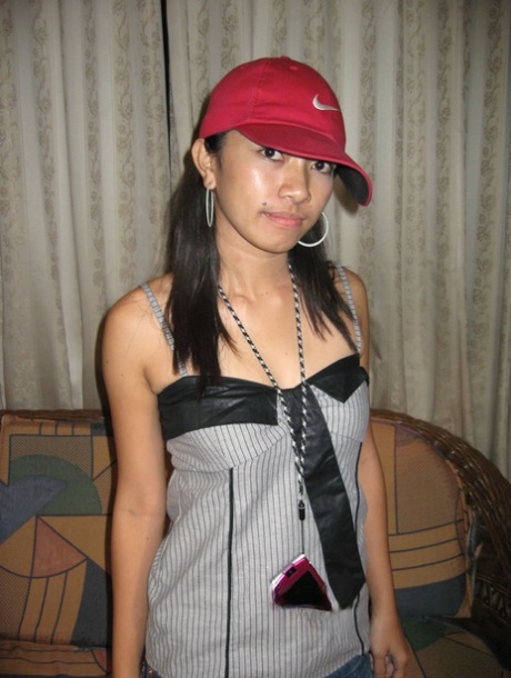 In her Nike baseball cap hat on the loveseat, young girl in the Pinay Islands takes off all her clothes.