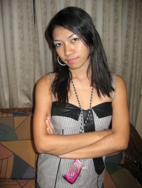 A piny Pinay girl removes her clothing on a loveseat while wearing only the Nike baseball cap.