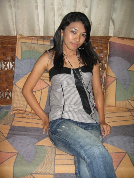 A young Pinay girl removes her clothing on a loveseat while wearing a Nike baseball cap.