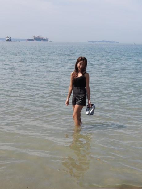 Chelsy, an Asian girl, wades through the ocean before making her first nude bed on a bed.