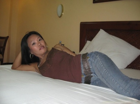 A middle-aged Filipino woman in her forties undresses herself to appear nude while lying on the bed.