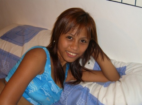 While on a bed, Filipina amateur removes her clothing for her first nude shoot.