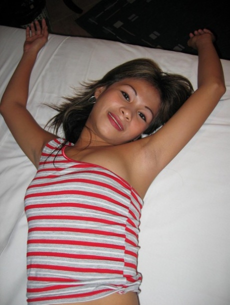 After removing a shirt, the Pinay bargirl poses in a bed with a strapless bra and jeans.