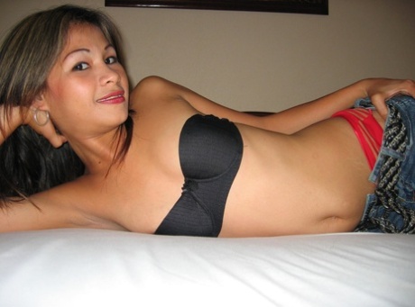 This pinay bargirl strips off despite the shirt to take pictures on a bed in an open sleeping bag with her jeans and strapless bra.