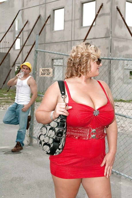 A construction worker puts on a kiss and cares for a tall blond bbw man in a red skirt.