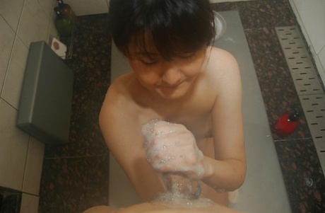 In the bathroom, a steamy asian MILF gives off a hot, soapy hand and blows her cock in an awkward pose.