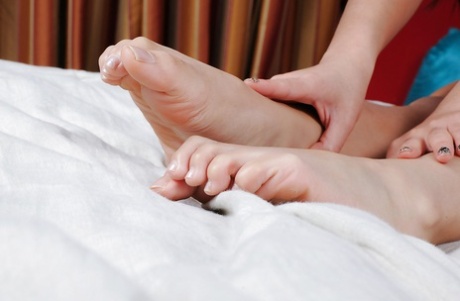 She's a small Asian girl who is naked with her feet on the floor and showing off her goods.