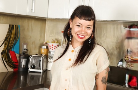 A smiley punk sweetheart undressing and teasing herself in the kitchen.